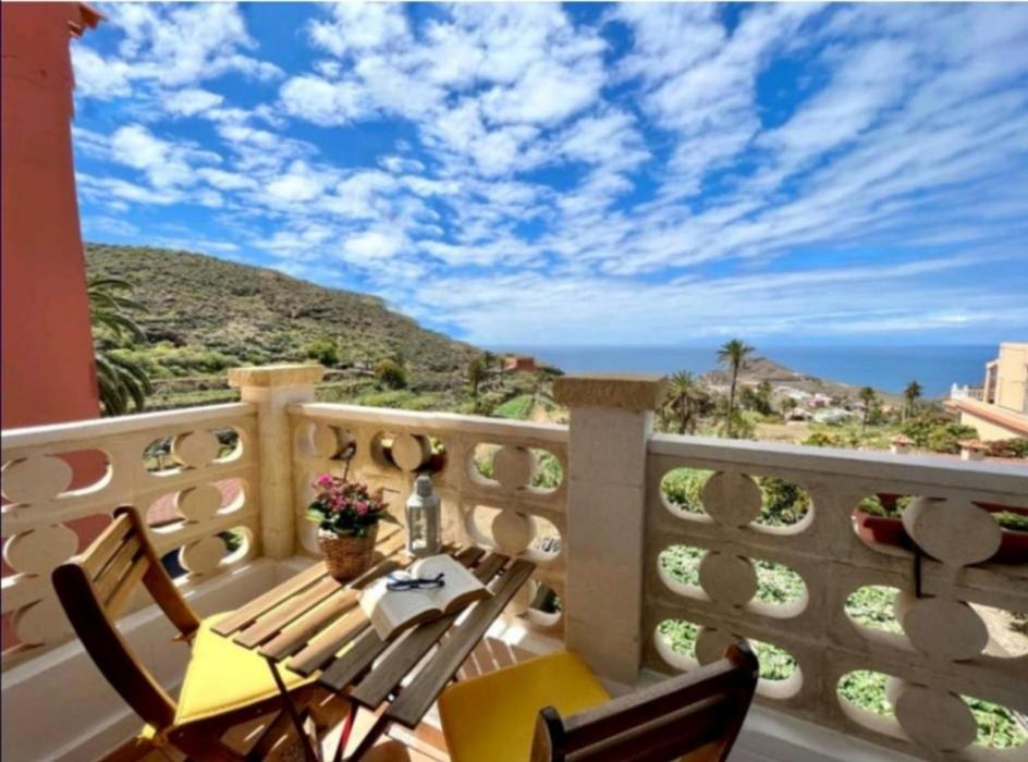balcón con mesa, sillas y vistas al océano en Casa María - Finca Medina en Alojera