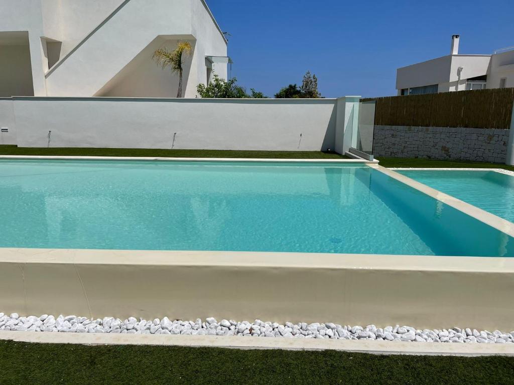 a blue swimming pool with rocks around it at Tuo Hotel in Polignano a Mare