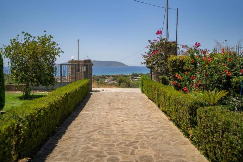 un chemin traversant un jardin avec des buissons et des fleurs dans l'établissement Donatos (Δονάτος), à Foinikounda