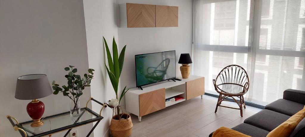 a living room with a tv and a chair at Apartamento Dindurra Centro Playa in Gijón