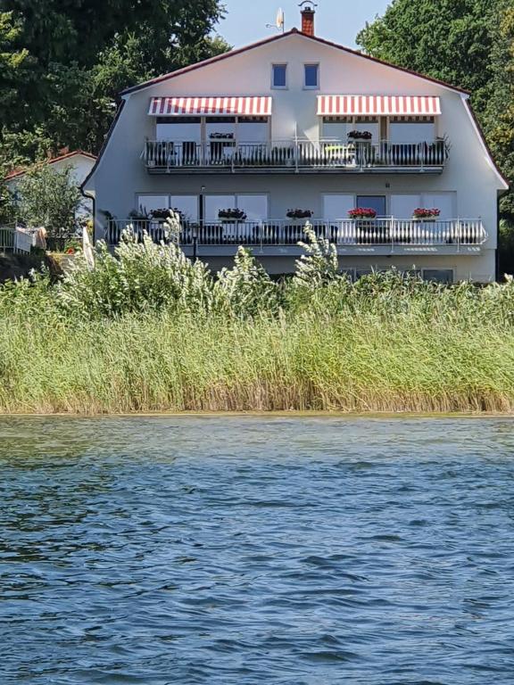 プラウ・アム・ゼーにあるVilla Seeschwalbe Plauの白い大きな建物で、水辺にバルコニーがあります。