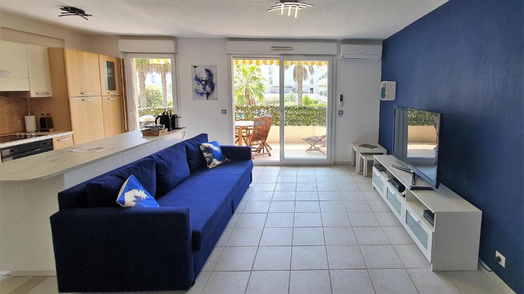 a living room with a blue couch and a kitchen at L'Atalante, 2 pièces 47m2 rénové résidence piscine in Villeneuve-Loubet