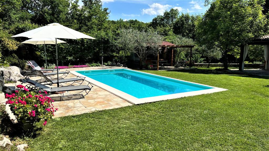 a swimming pool in a yard with a umbrella and chairs at Holiday Home Casa Dei Farfui in Momjan