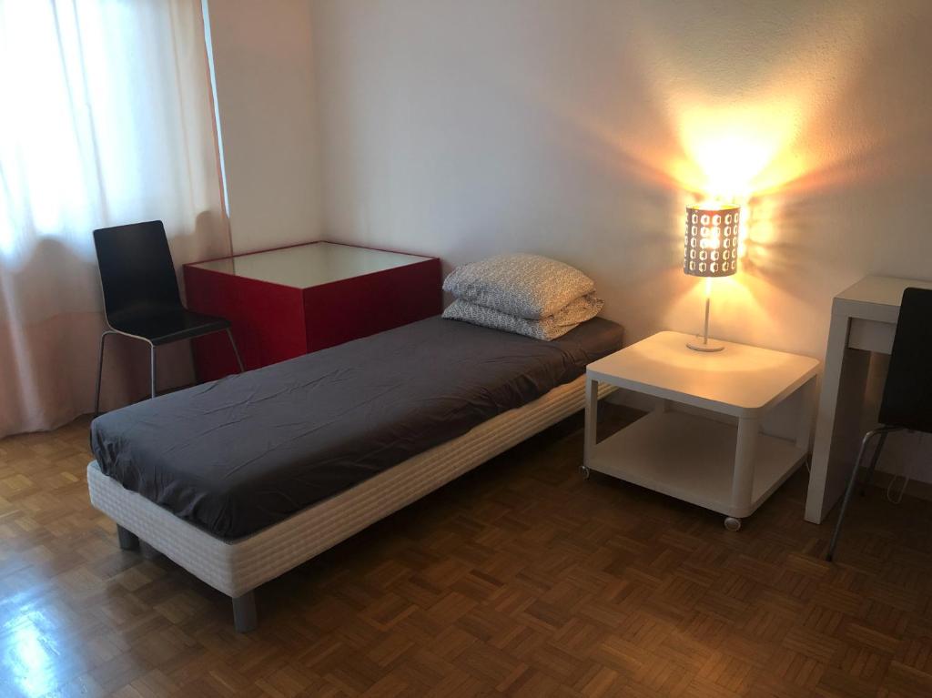una piccola camera con letto, tavolo e lampada di Canevascini a Lugano
