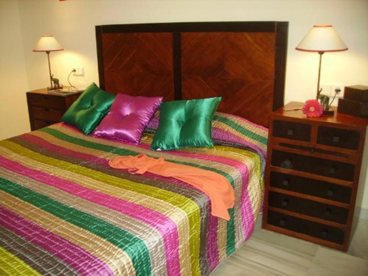 a bed with green and purple pillows on top of it at Málaga, Mijas, La Cala, apartamento vacaciones de ensueño in La Cala de Mijas
