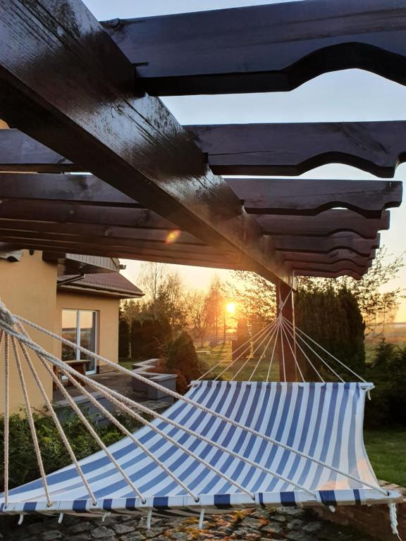 a hammock in a yard with the sunset in the background at Sunset Holidays - Dom nad Jeziorem in Żarnowska