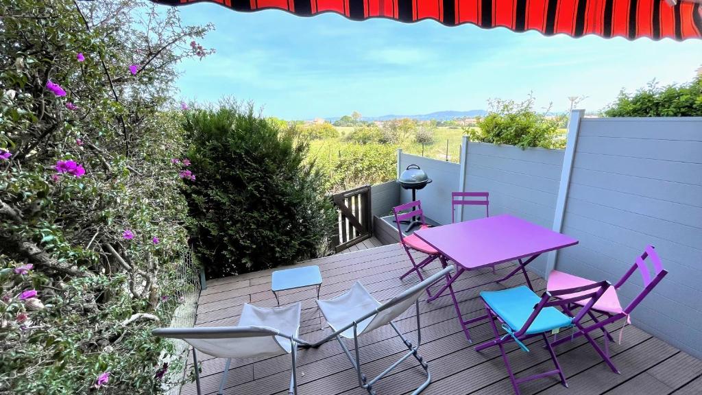 une table et des chaises roses sur une terrasse en bois dans l'établissement L'escale, à Carqueiranne