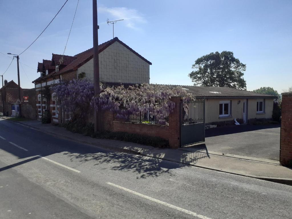 una cerca con flores púrpuras en un lado de una casa en 14-18 Somme Chambres, en Beaucourt-sur-lʼAncre