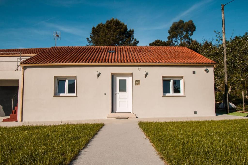 una pequeña casa blanca con techo rojo en Casa O Souto, en Mazaricos