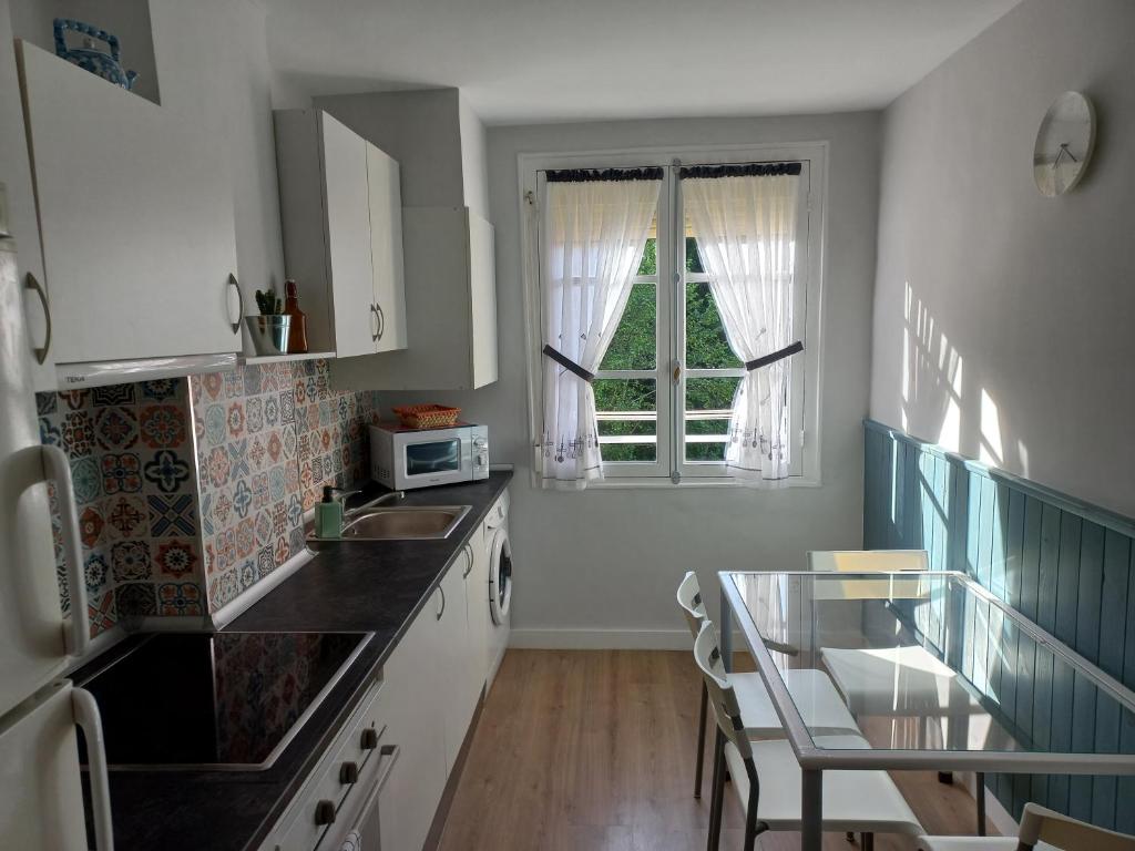 een keuken met witte kasten en een glazen tafel bij Monte Sueve in Arriondas