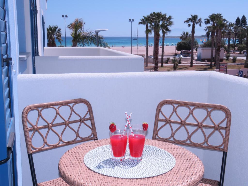 Una mesa con dos bebidas en un balcón con vista a la playa. en Al Manara Holiday - Appartamenti fronte mare, en San Vito lo Capo
