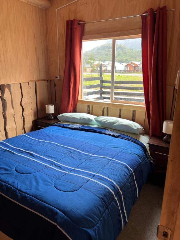 a bedroom with a blue bed and a window at Cabaña marteo in Chaitén