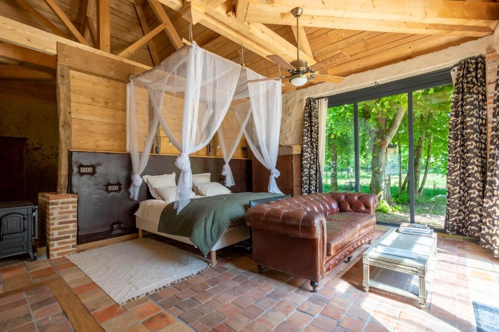 a bedroom with a canopy bed and a couch at Manoir de la Mazeraie lodge de luxe Loire Valley in Joue-les-Tours