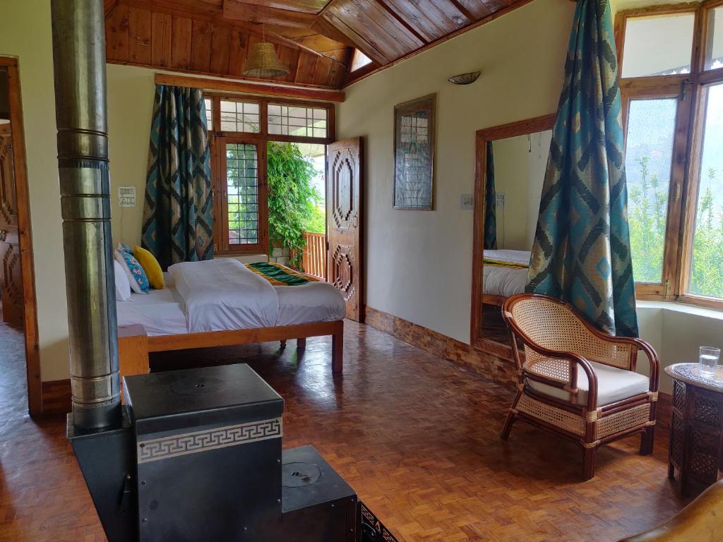 a living room with a wood stove and a bed at Cliffer Cottage: Make Mountains Memorable! in Manāli