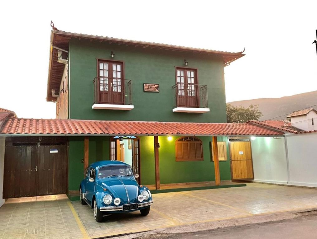 an old blue car parked in front of a green house at Pouso da Paz in Tiradentes