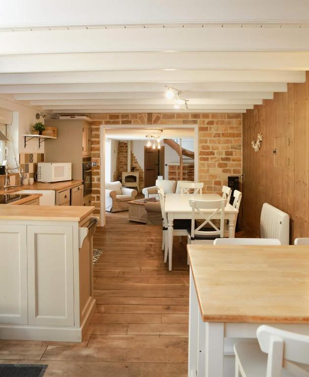 Il comprend une cuisine et un salon avec des tables et des chaises blanches. dans l'établissement Le doux refuge, à Rimboval