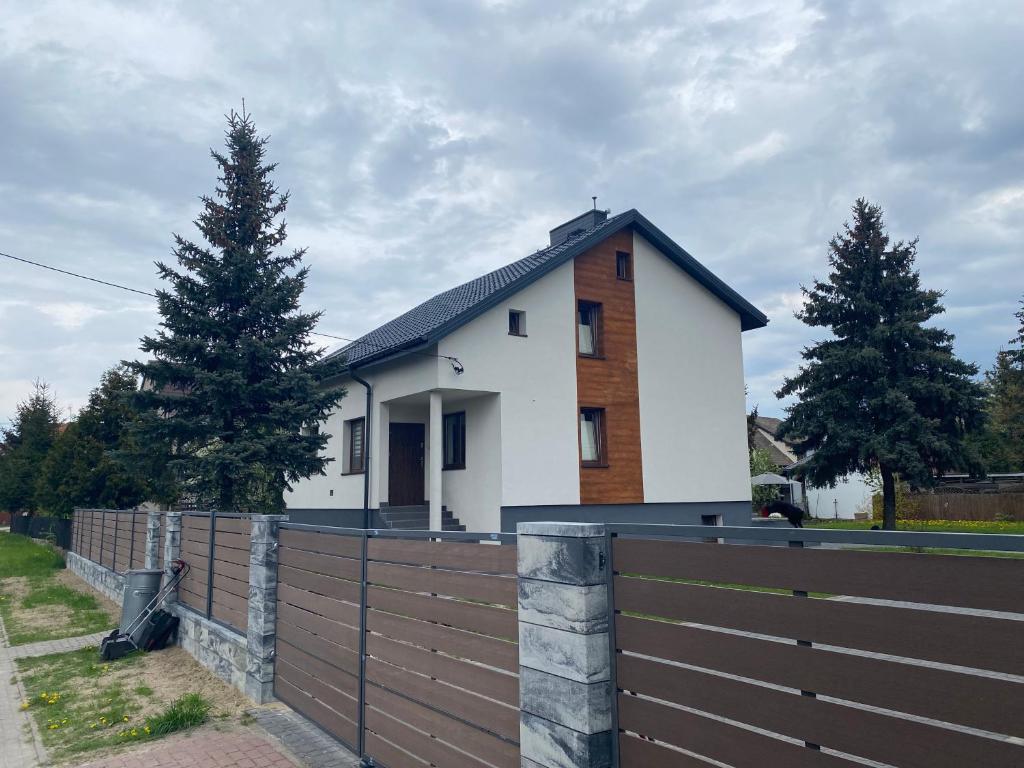 a white house behind a wooden fence with a fence at Pokoje na Jaśminowej in Pisz