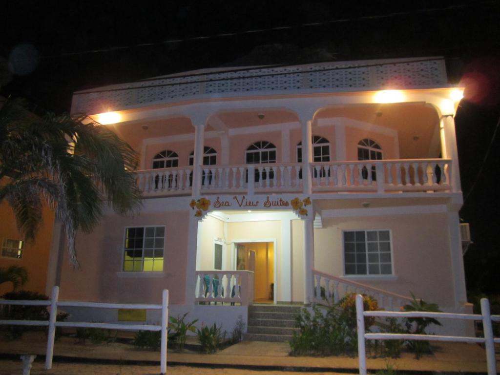 a white house with a balcony at night at Sea View Suites in Placencia