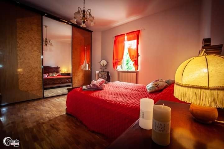 una camera con letto rosso e tavolo con lampada di La Pergola del Grottino a Torgiano