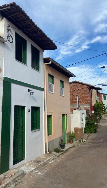 a white building with green doors on a street at Casalê in Lençóis