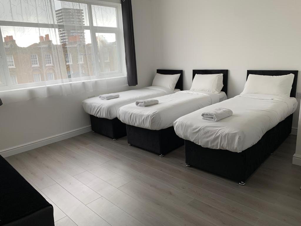 3 camas sentadas en una habitación con ventana en Comfortable - Cosy - Budget Studios in City Center, en Londres