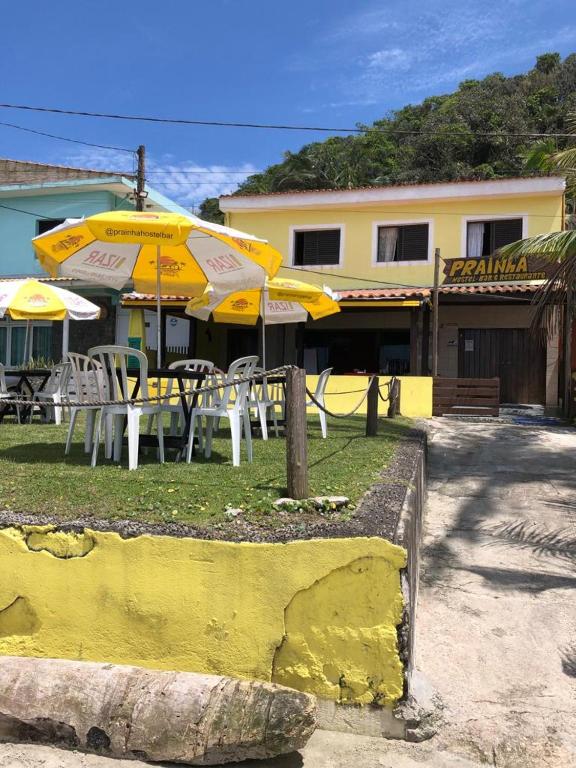 a table and chairs with umbrellas in front of a building at Prainha Pousada - Bar e Restaurante in Itanhaém