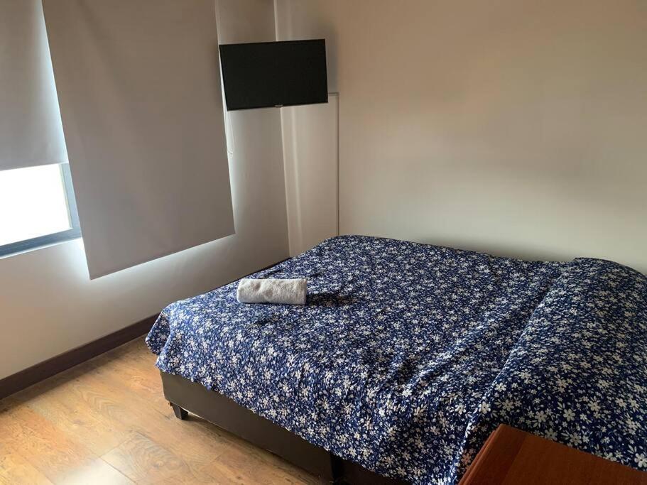 um pequeno quarto com uma cama com um edredão azul em Apartamento tipo boutique por el CC Titán Plaza em Bogotá