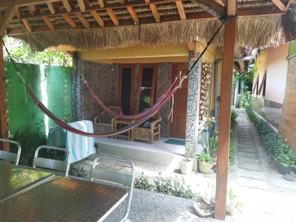a porch of a house with a table and chairs at Pelangi Homestay Bungalow Gili gede in Sekotong