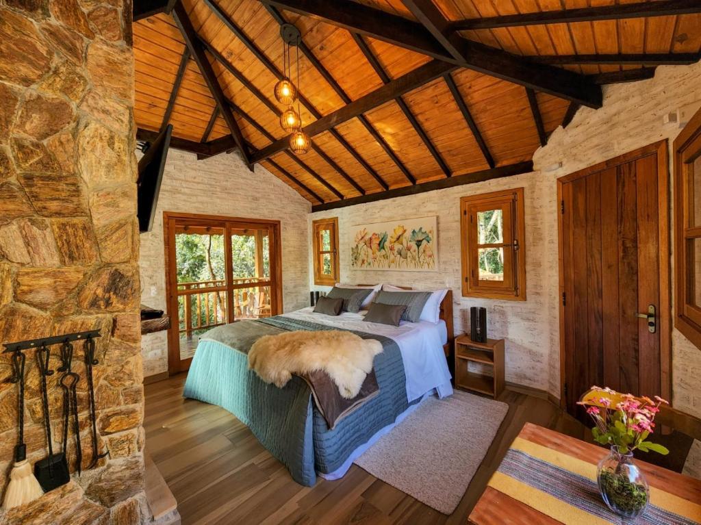 a bedroom with a bed and a stone wall at Pousada Cabana na Floresta - Monte Verde in Camanducaia