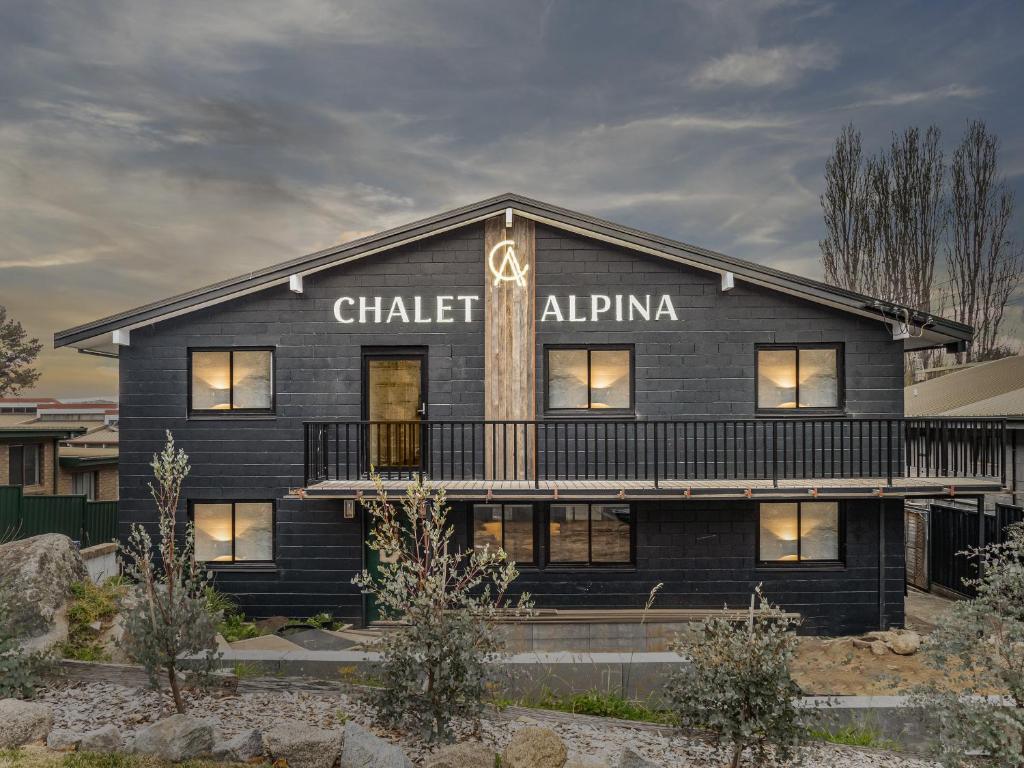 ein schwarzes Gebäude mit den Worten „Chalk alpin“ darauf in der Unterkunft Chalet Alpina in Jindabyne