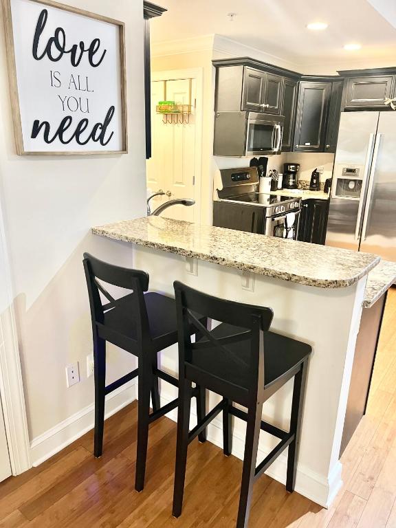 a kitchen with a counter and two black chairs at COZY DOWNTOWN APARTMENT-Naval Academy Vicinity in Annapolis