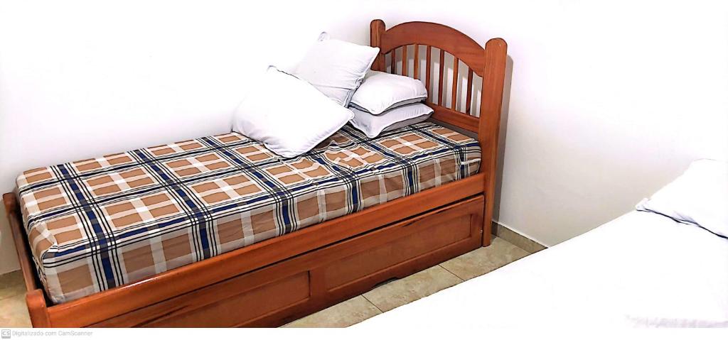 uma cama de madeira com duas almofadas em Apartamento Cabo Frio 2 QUARTOS 250 METROS DA RODOVIÁRIA em Cabo Frio