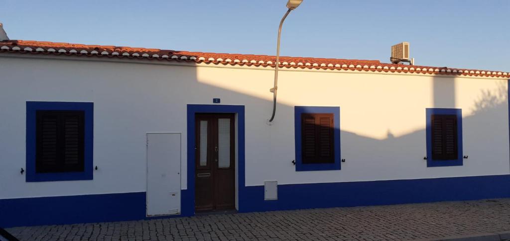 biały budynek z drzwiami i dwoma oknami w obiekcie Recanto da Luz w mieście Luz