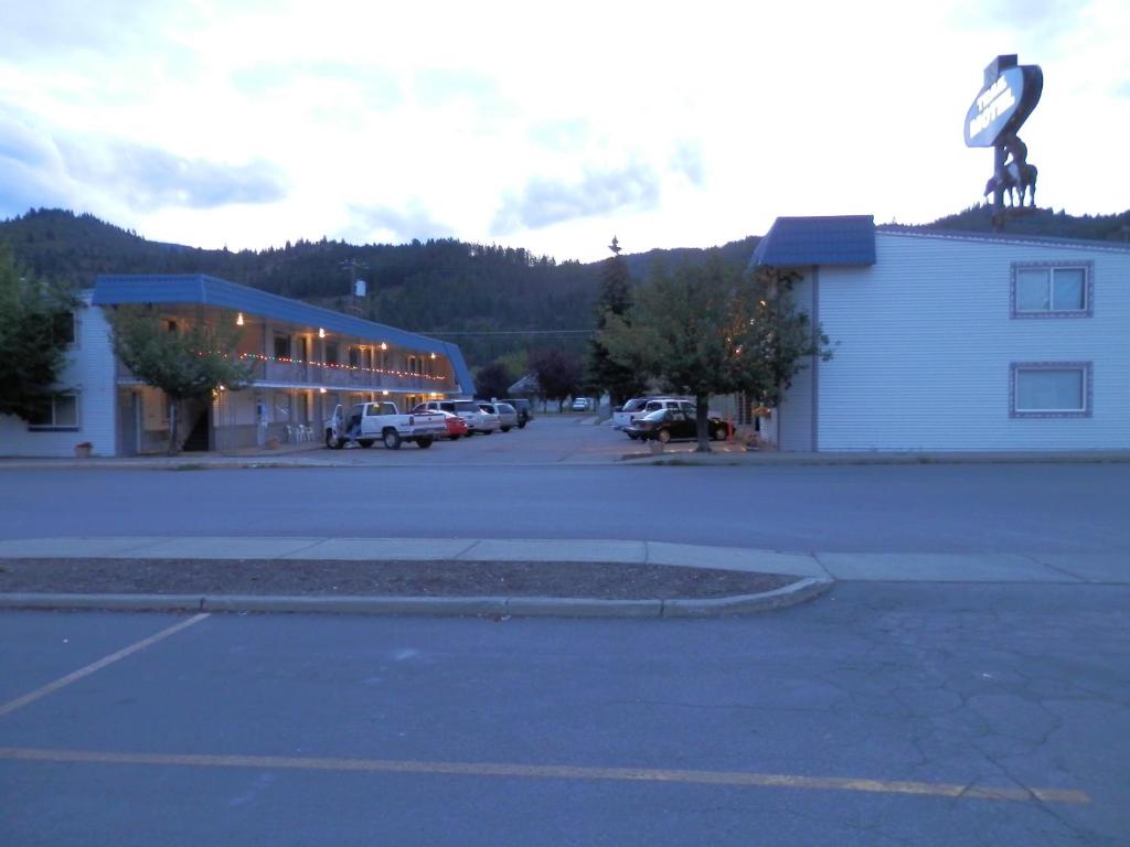 um parque de estacionamento em frente a um edifício com uma estátua em Trail Motel em Kellogg