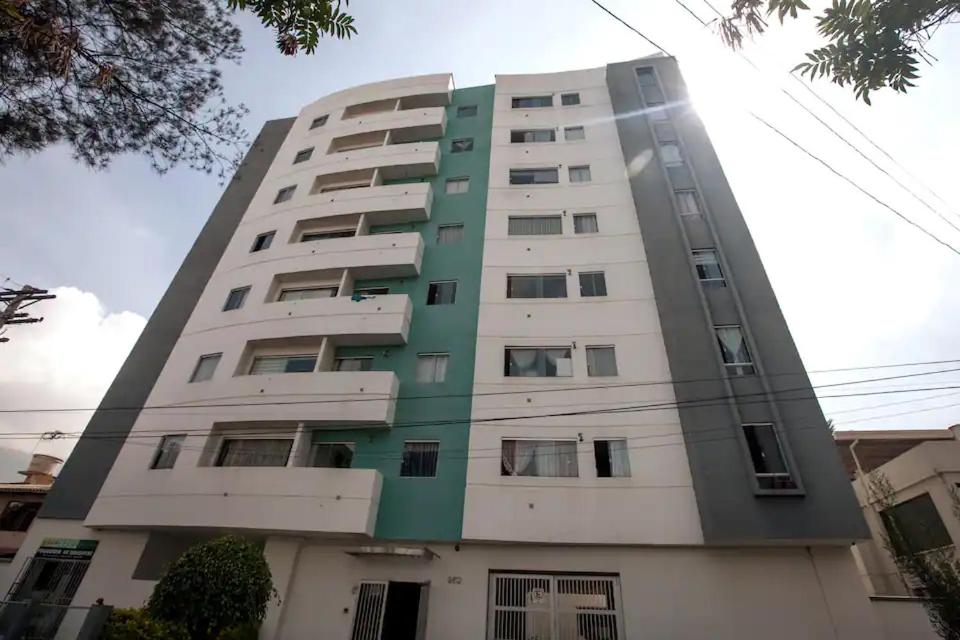 wysoki budynek apartamentowy z zielonymi i białymi w obiekcie Departamento bien ubicado con 2 habitaciones con camas dobles w mieście Cochabamba