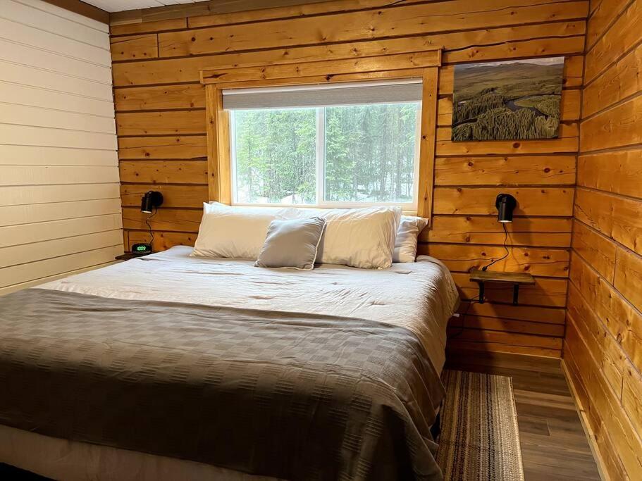 Bett in einem Holzzimmer mit Fenster in der Unterkunft Aurora Ridge Cabin in Fairbanks