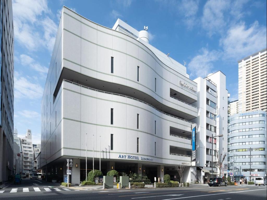 a white building on a street in a city at ART HOTEL Nippori Lungwood in Tokyo
