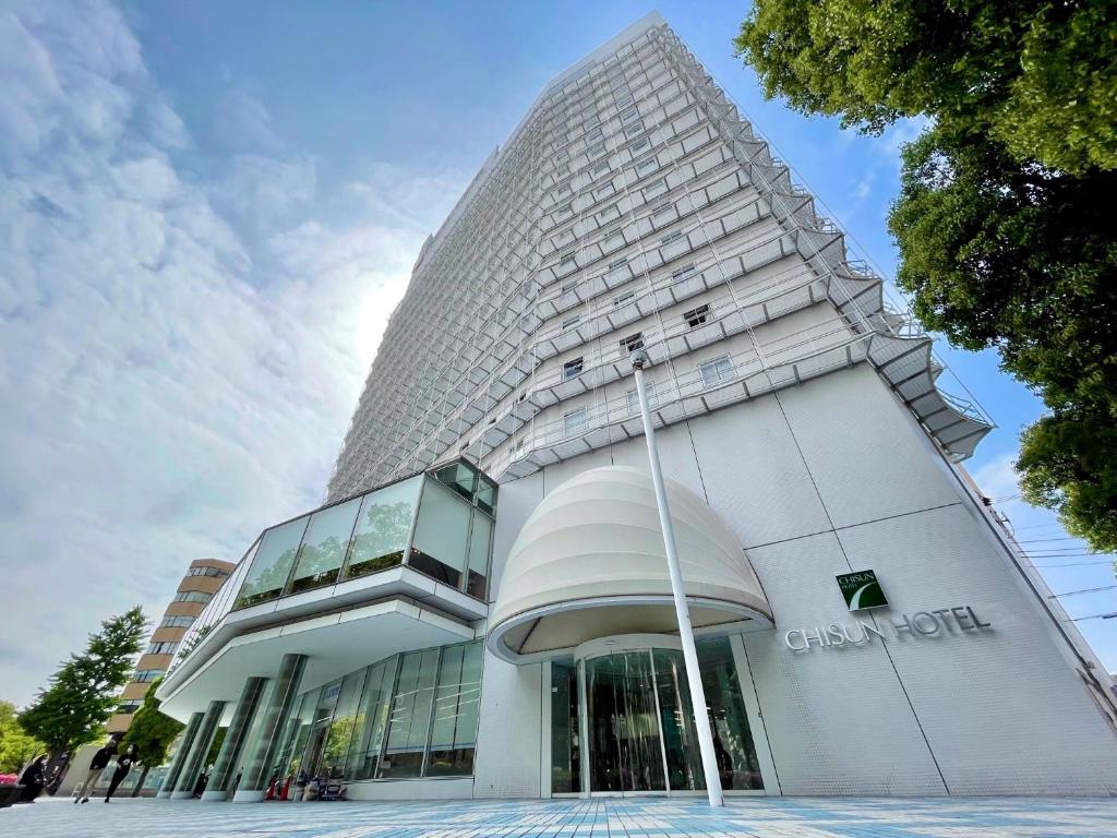 a tall white building with a glass facade at Chisun Hotel Yokohama Isezakicho in Yokohama
