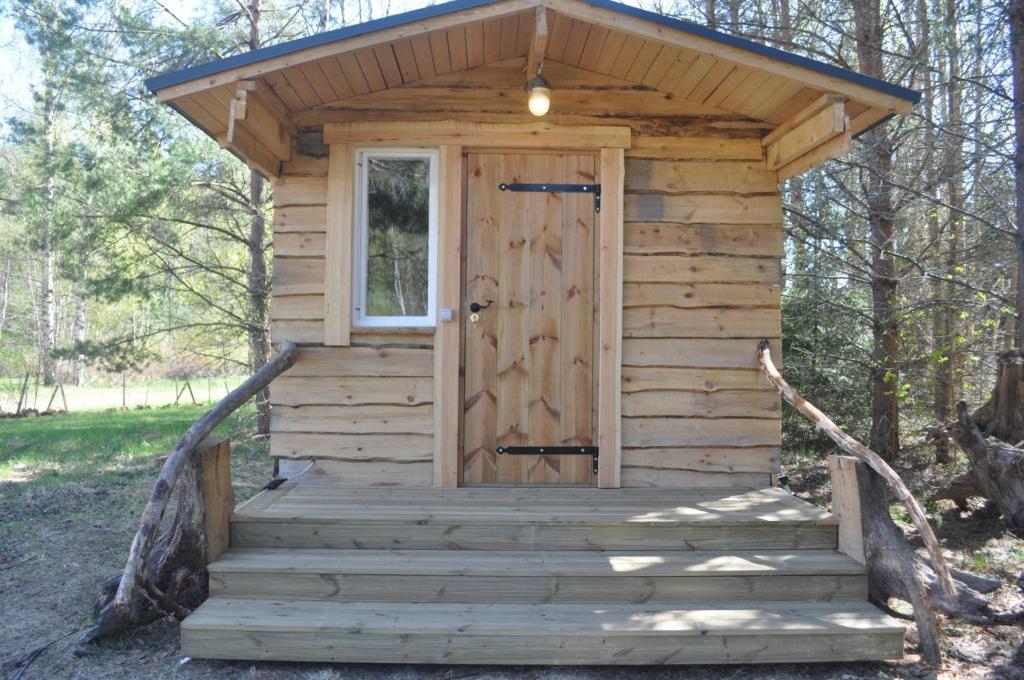 una casa exterior de madera con puerta y escaleras en Korjuse Moori metsaonn- forest hut, en Korjuse