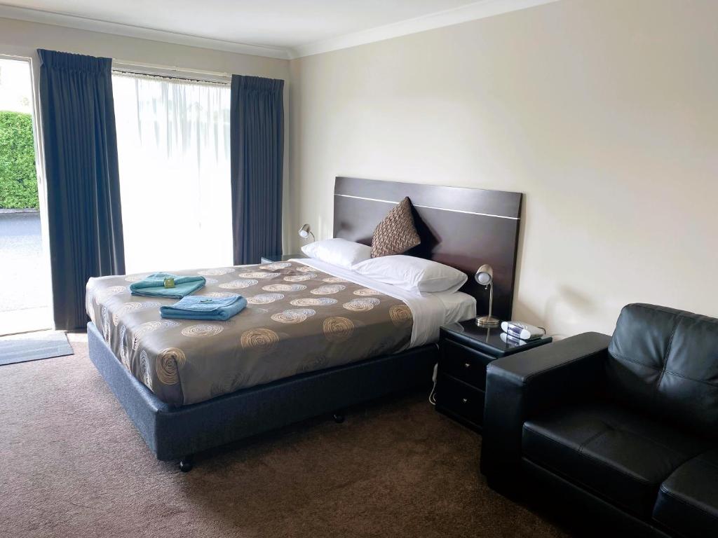 a bedroom with a bed and a couch and a chair at Dalvue Motel in Terang