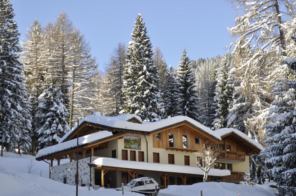 uma casa coberta de neve numa floresta nevada em Casa del Roccolo em Folgarida