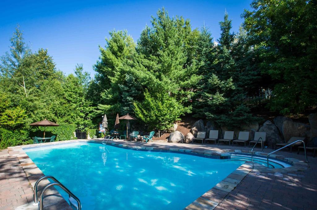 a swimming pool in a yard with chairs and trees at Lodge de la Montagne in Mont-Tremblant