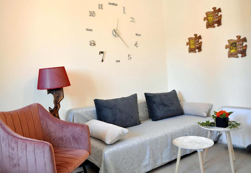 a living room with a couch and a clock on the wall at Nefelis Home in Koskinou