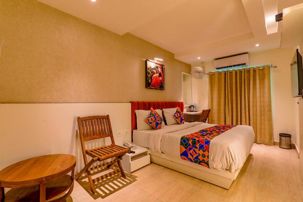 een slaapkamer met een bed, een tafel en een stoel bij FabHotel Geetraj in Lucknow