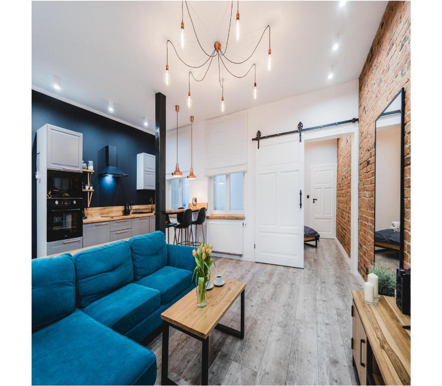 Una sala de estar con un sofá azul y una mesa. en Modern Apartments Toruń 2 Stare Miasto-Centrum, en Toruń