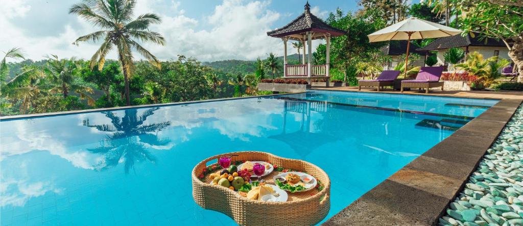 a basket of food sitting on the edge of a swimming pool at Akusara Jungle Resort And Spa in Nusa Penida