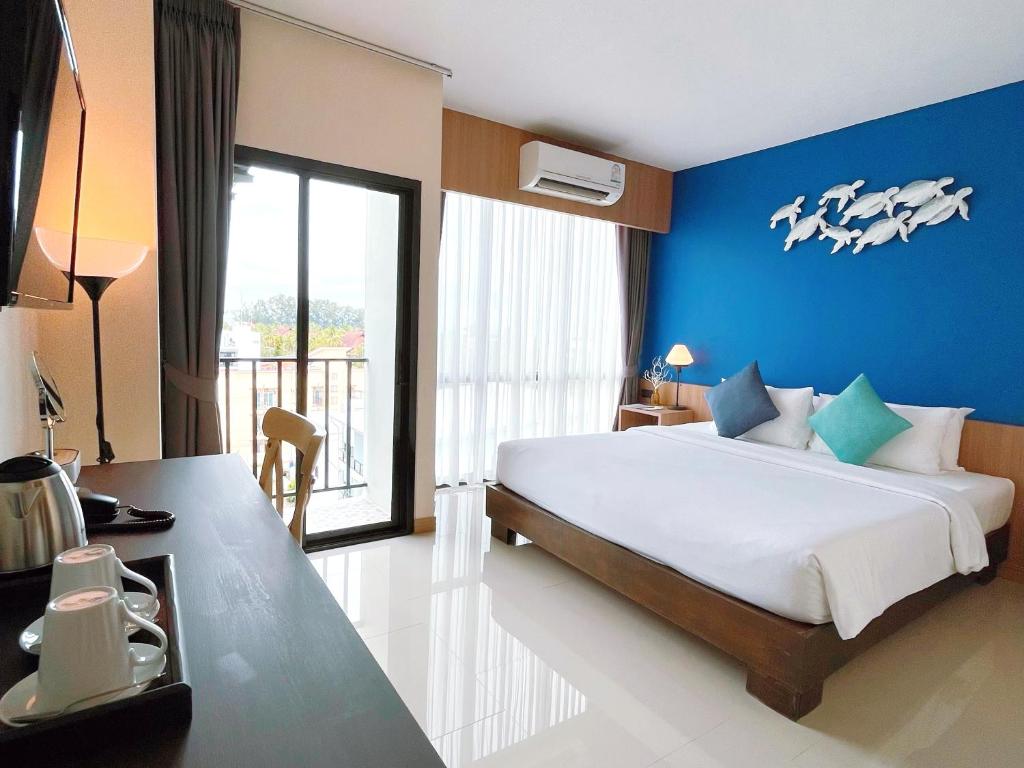 a bedroom with a large bed with a blue wall at The Sixteenth Naiyang Beach Hotel SHA Plus in Nai Yang Beach