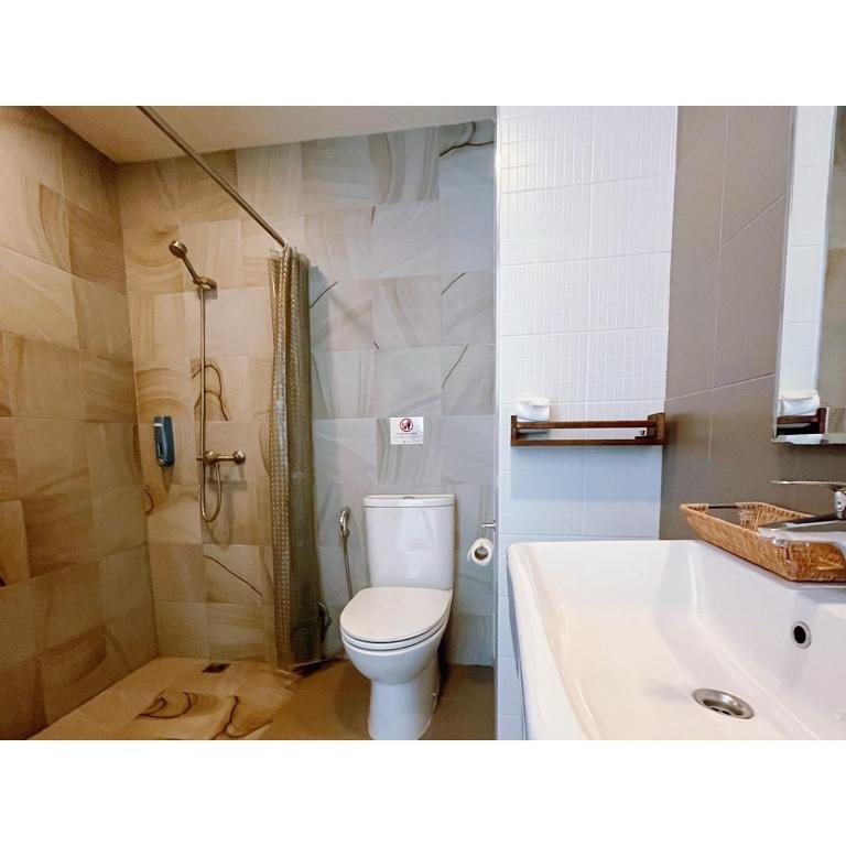 a bathroom with a toilet and a shower and a sink at The Sixteenth Naiyang Beach Hotel SHA Plus in Nai Yang Beach