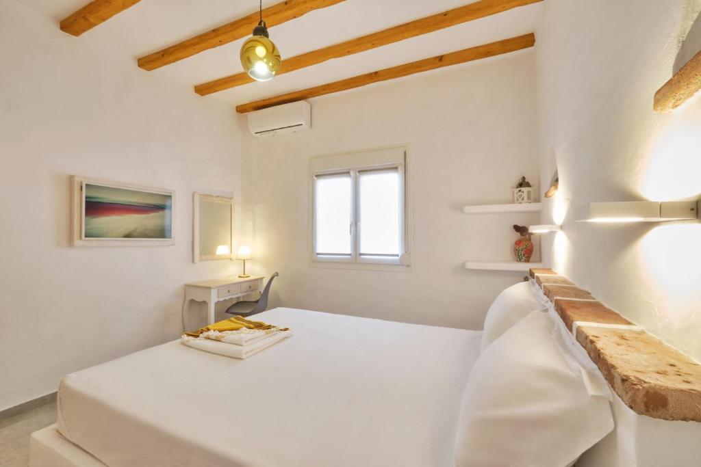 a white room with a bed and a window at Eressian Lodgings, Skala Eressos Beach in Skala Eresou
