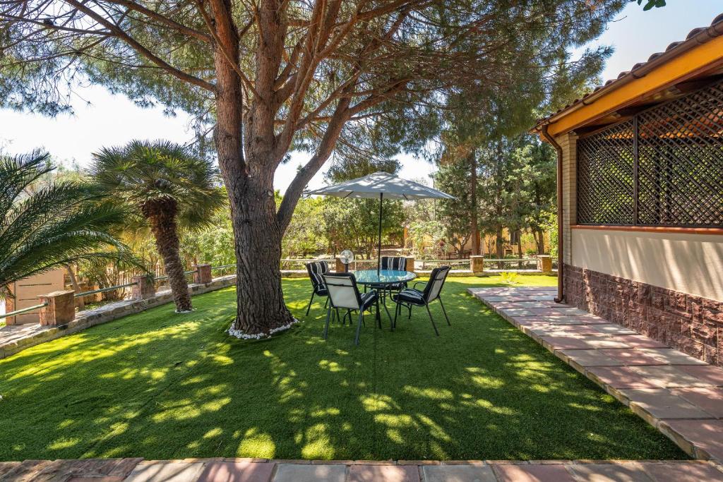 eine Terrasse mit einem Tisch und Stühlen unter einem Baum in der Unterkunft Villa Lidia vicino al mare in Solanas